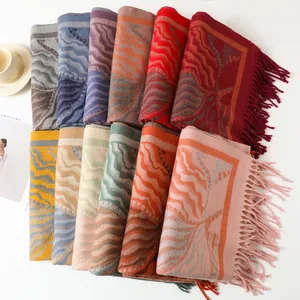Detailed view of thick winter knit shawls with wave patterns and long tassel fringes
