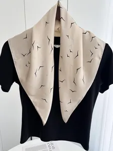 Detail of lightweight beige silk scarf featuring elegant black bird prints on a black shirt