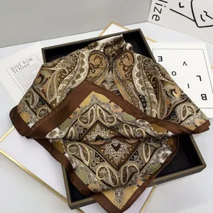 Elegant silk-textured paisley square scarf in brown and gold on a minimalist tray