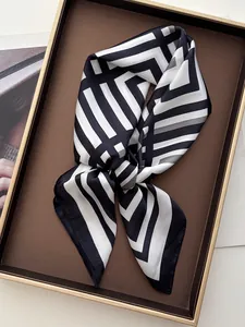 Dettaglio del foulard di seta a righe bianche e nere piegato in un vassoio di lusso