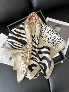 Detail of silk-like leopard and zebra print scarf elegantly draped on a black tray