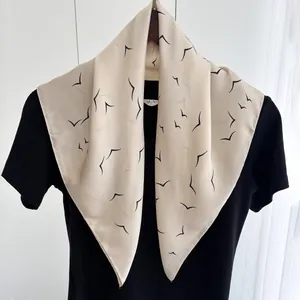 Detailed view of square silk scarf with black bird prints hanging on a hanger
