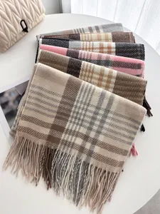 Gros plan d'écharpes à carreaux empilées avec pompons et texture douce multicolore