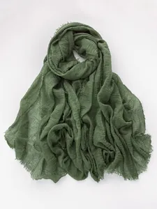 Detailed close-up of dark green cotton linen scarf with soft frayed edges and pleated texture