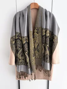 Macro shot of ethnic jacquard shawl with tassel fringe on grey and gold floral pattern