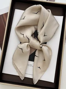 Close-up of champagne silk square scarf with minimalist bird print in a gift box