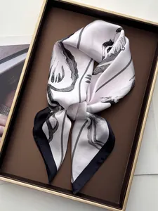 Detail of silk square scarf featuring black starfish print and contrast hem on beige fabric
