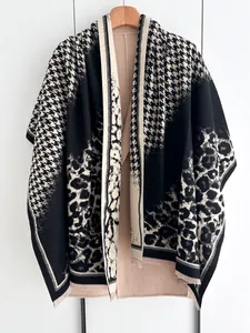 Detailed close-up of leopard and houndstooth pattern knit shawl with fringe edge