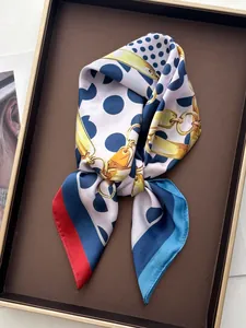 Detailaufnahme eines weißen Seidenschals mit blauen Punkten und goldenem Kettenmuster-Print