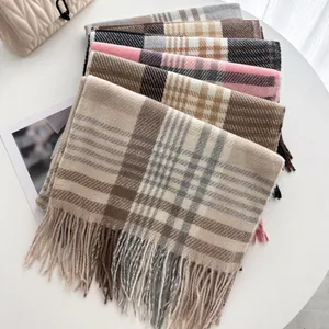 Pile d'écharpes à carreaux et à franges de couleurs variées sur un décor de table blanc