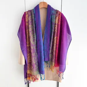 Detailopname van bohemien paisley sjaal met kleurrijke kwastjes op een wollen jas