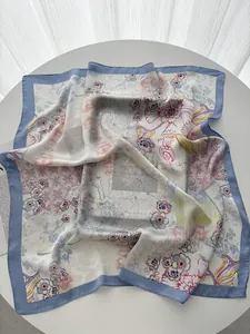 Detail of floral and typography patterns on a silky square scarf displayed on a table