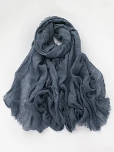 Close-up of gray blue linen scarf showing natural wrinkled texture and frayed edge detail