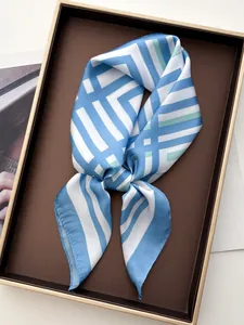 Dettaglio foulard in seta a righe blu e verdi in un'elegante confezione regalo marrone