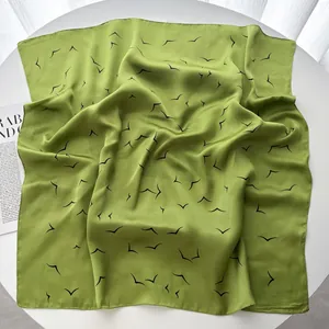 Detailed view of green satin square scarf with seagull print on white table