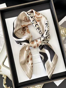 Detailed view of champagne satin scarf with leopard spots and abstract wave patterns