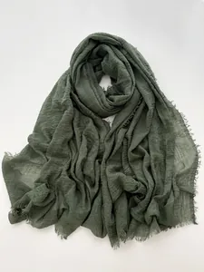 Detail of dark olive green cotton linen scarf with textured fringe and raw edges