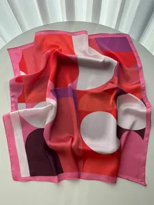 Detailed shot of vibrant geometric pattern silk scarf draped on a white display stand