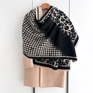 Close-up of leopard and houndstooth pattern pashmina shawl draped on an ivory coat