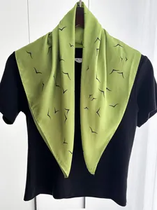Close-up of lightweight green square silk scarf with bird print on black t-shirt