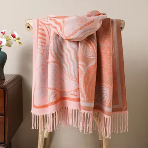 Detail of pink and orange knit shawl with leaf patterns and thick tassel fringe