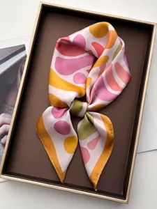 Close-up of silk-textured square scarf with colorful geometric patterns in a gift box