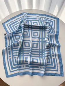 Dettaglio di sciarpa in seta azzurra con motivi a righe geometriche su tavolo bianco