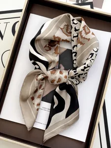Detail of a leopard and tiger print silk scarf tied in a knot inside a gift box