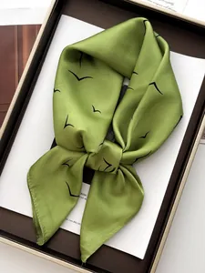 Detail of green silk scarf with black bird print in premium gift box packaging