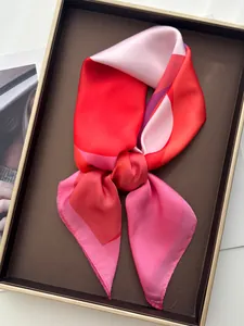 Detail of silk-like square scarf with geometric red and purple blocks on a tray