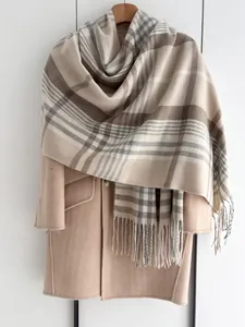 Détail d'une écharpe à carreaux doux avec franges sur un manteau en laine beige