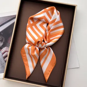 Dettaglio di un foulard di seta a righe arancioni e bianche su un vassoio lussuoso