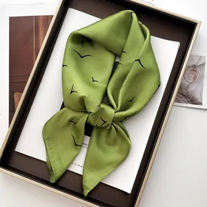 Macro detail of grass green satin silk scarf with black seagull print tied in a bow