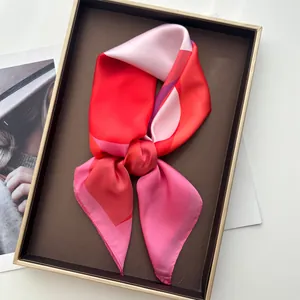 Macro detail of geometric patterned silk scarf neatly folded in a luxury gift box
