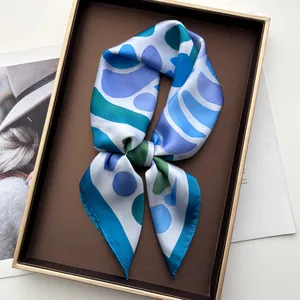 Detailed view of geometric blue silk scarf in a premium gold-trimmed gift box