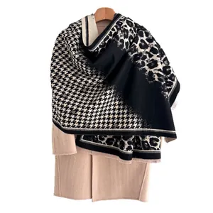 Thick leopard and houndstooth pattern scarf draped on a beige coat over wood hanger