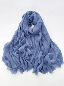 Detailed texture of blue cotton linen scarf with natural crinkles and frayed fringe edge