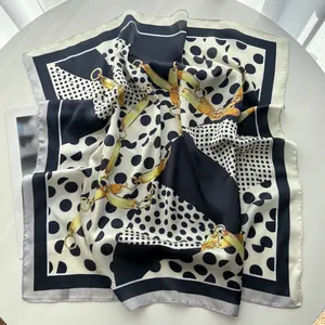 Detailaufnahme von Seidenschal mit schwarz-weißen Punkten und goldenen Kettenmustern