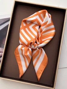 Dettaglio di elegante sciarpa di seta a righe arancioni e bianche in confezione regalo