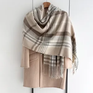 Détail d'une écharpe à carreaux beige avec franges sur un manteau en laine chic