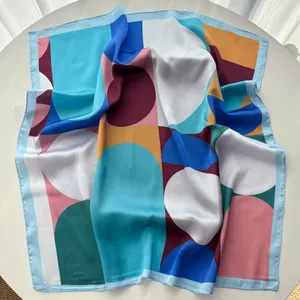 Detail of elegant satin square scarf with geometric dots and hand-rolled blue edges