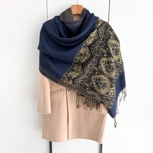 Detailed close-up of dark blue ethnic shawl fabric with golden floral texture and fringe