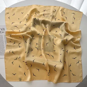 Artistic detail of ginger yellow silk scarf with minimal seagull print on table