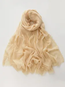 Detail of light yellow cotton linen scarf featuring natural crinkle texture and fringed edges