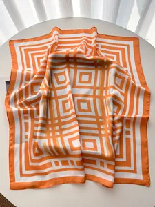 Dettaglio di un foulard in seta quadrato con motivo geometrico moderno arancione e bianco