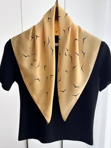 Detailed view of yellow chiffon neck scarf with black bird prints on black t-shirt