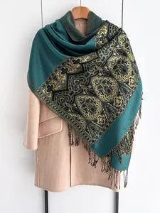 Close-up of ethnic paisley pattern and fringe detail on dark green winter shawl