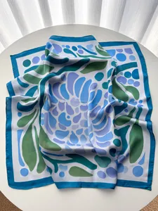 Macro detail of silky square scarf with blue and green abstract floral patterns