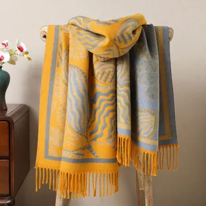 Detail of elegant autumn shawl with leaf patterns and fringes draped on wooden chair