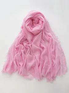 Detail of light pink cotton linen scarf featuring frayed edges and natural crinkle texture
